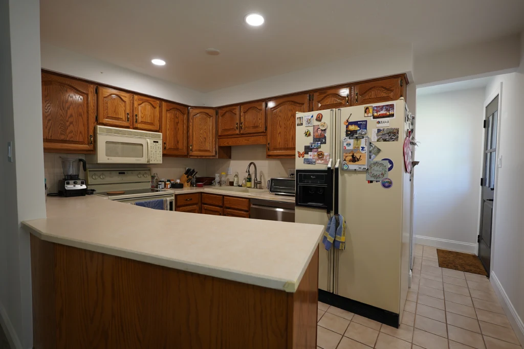 Before kitchen remodel on W 107th Ave in Westminster, CO 80021 showing dated oak cabinets, laminate peninsula countertop, tile floor, and older appliances.