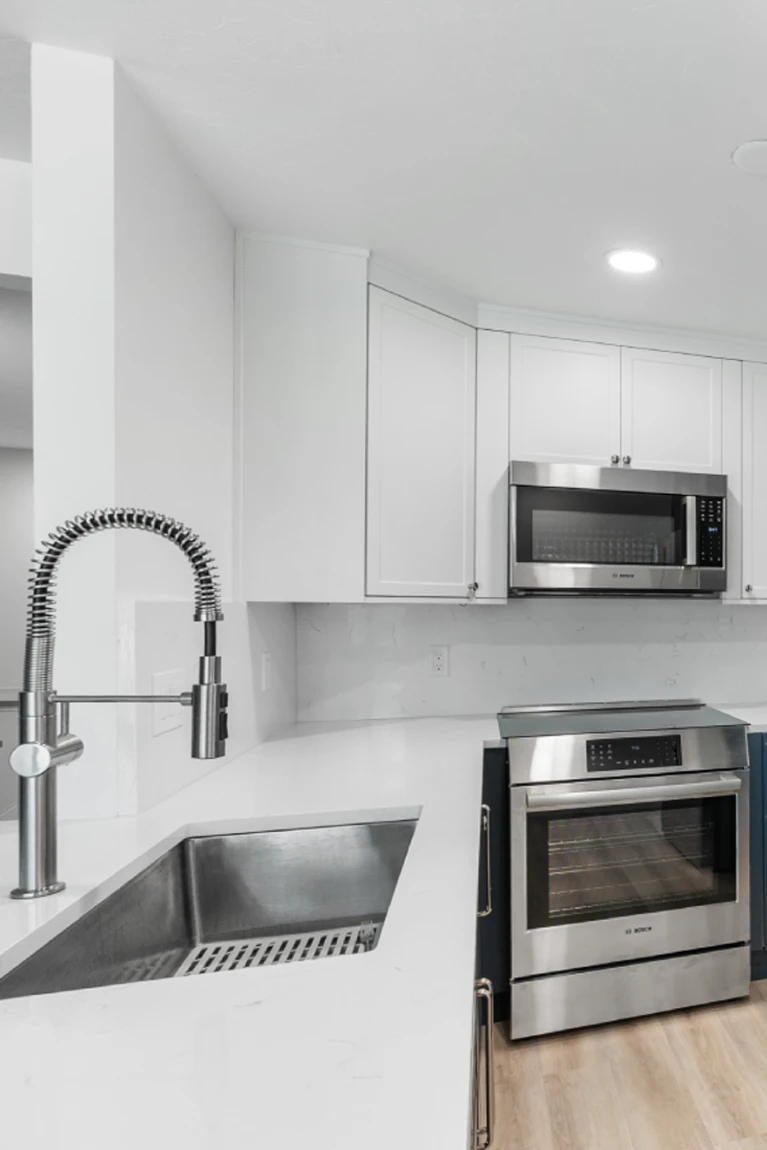 Modern kitchen remodel in Denver featuring white quartz countertops, a stainless steel industrial faucet, and Bosch appliances.