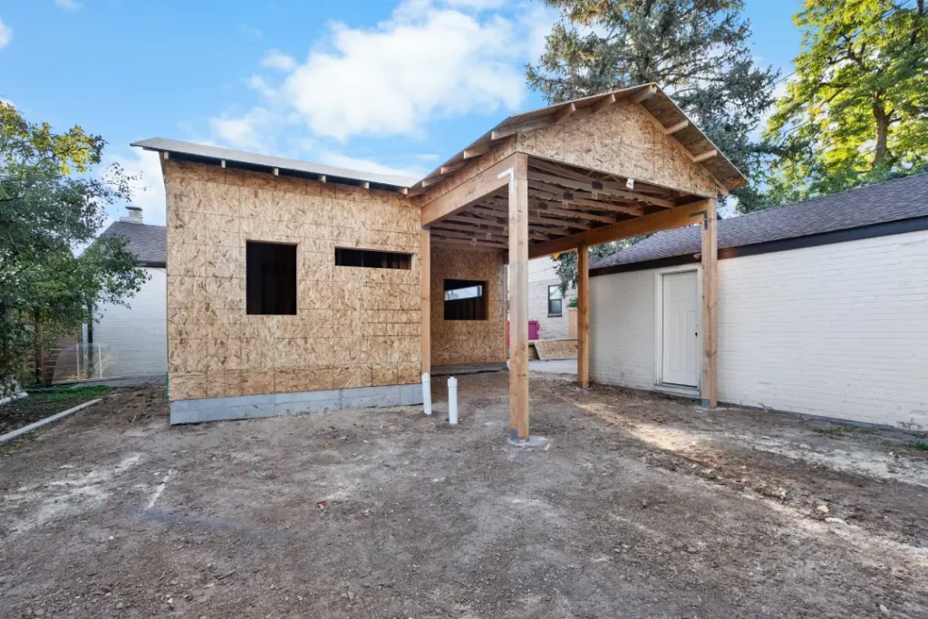 Framing phase of a detached ADU construction project at 433 Holly St, Denver, CO 80220, featuring plywood sheathing and a covered patio structure by Verified Builders.