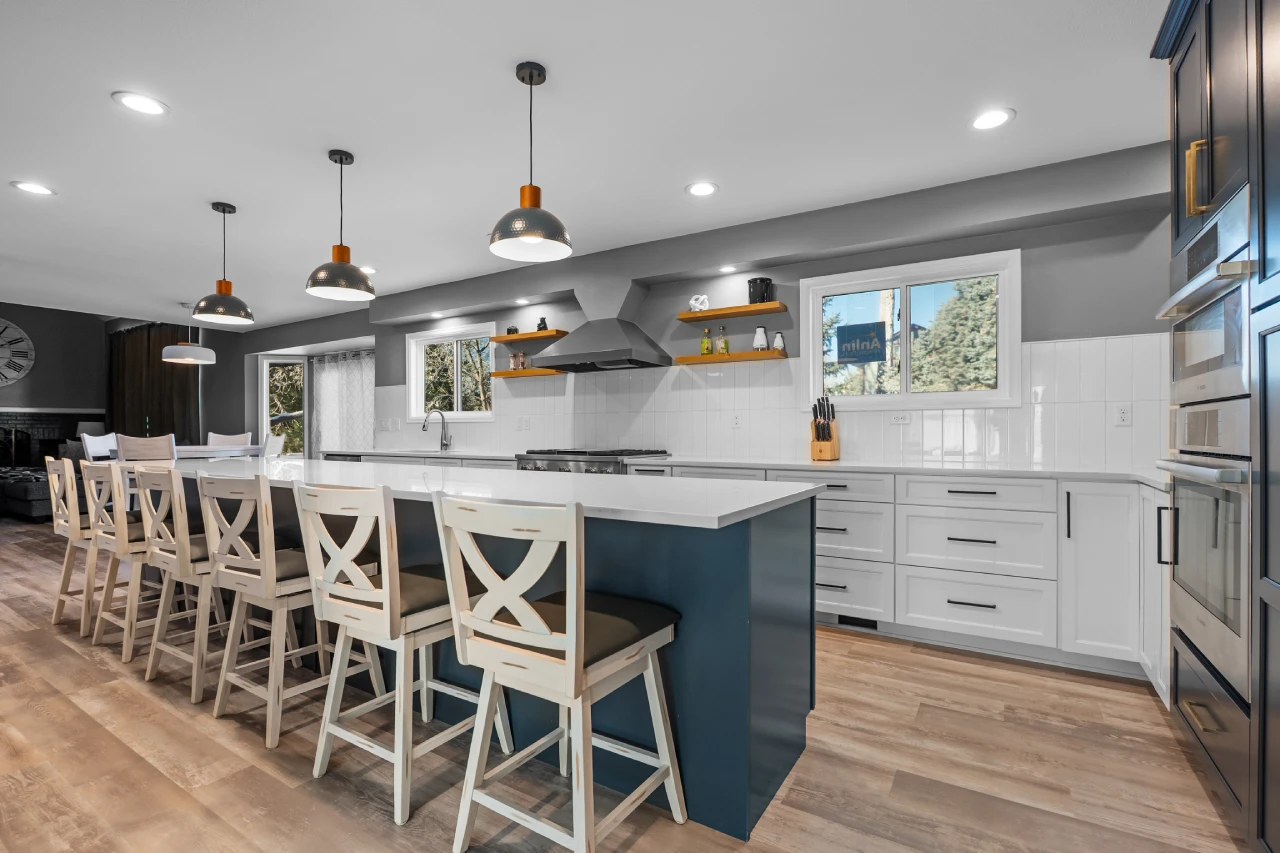 Completed Main Floor Remodel in Parker, CO 80138 featuring an open-concept luxury kitchen with a massive midnight blue island, white perimeter cabinetry, and seamless LVP flooring connecting the dining and living areas.
