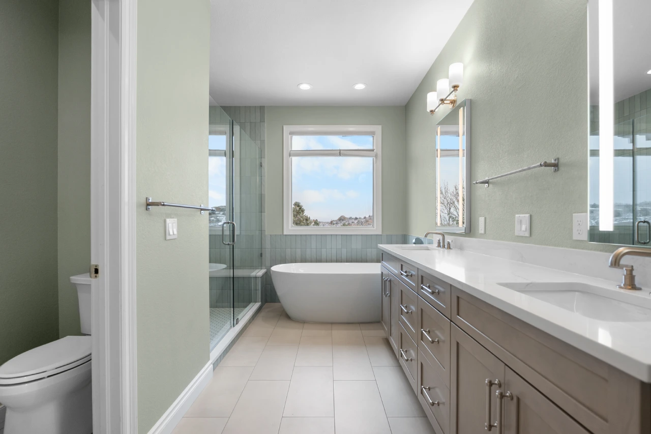 Completed master bathroom remodel in Littleton, CO 80125 featuring a white freestanding tub, sage green vertical tile, custom glass shower, and Pental Quartz vanity.