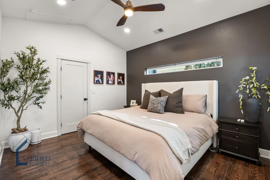 Completed primary suite interior by Verified Builders in Denver, CO, featuring vaulted ceilings, a dark accent wall, and hardwood floors that blend seamlessly with the existing home.