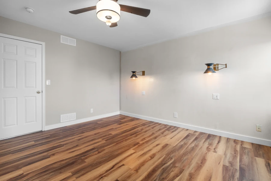 After photo of a soundproofed master bedroom in Northglenn, CO. Featuring new warm oak LVP flooring, Sherwin-Williams Repose Gray walls, and mid-century modern sconces installed by Verified Builders.