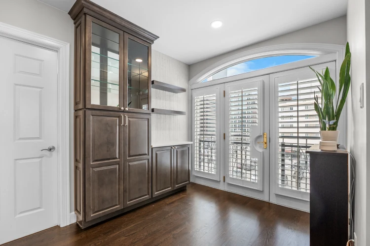Custom built-in cabinet and beverage area beside arched balcony doors in a remodeled Denver living space