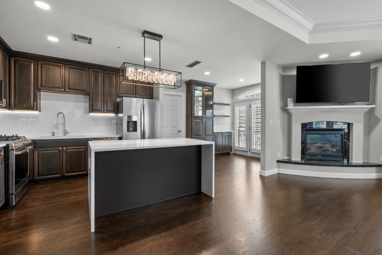 Open-plan Denver kitchen remodel with waterfall island, dark cabinetry, hardwood floors, and fireplace
