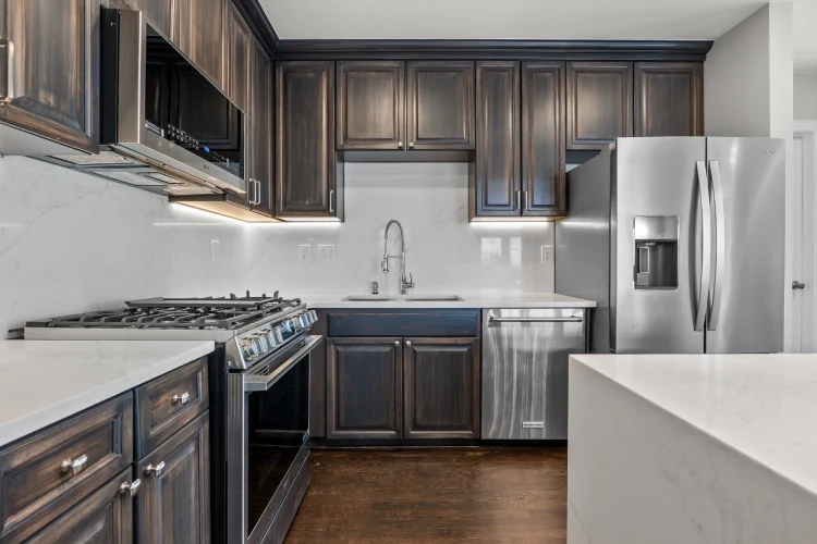 Kitchen remodel in Denver with dark refinished cabinets, quartz backsplash, stainless appliances, and hardwood floors