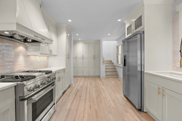 Custom kitchen painted in Kashmir by Portola Paints with Miele range, custom hood, floor-to-ceiling pantry wall, and brushed brass hardware in Wash Park renovation
