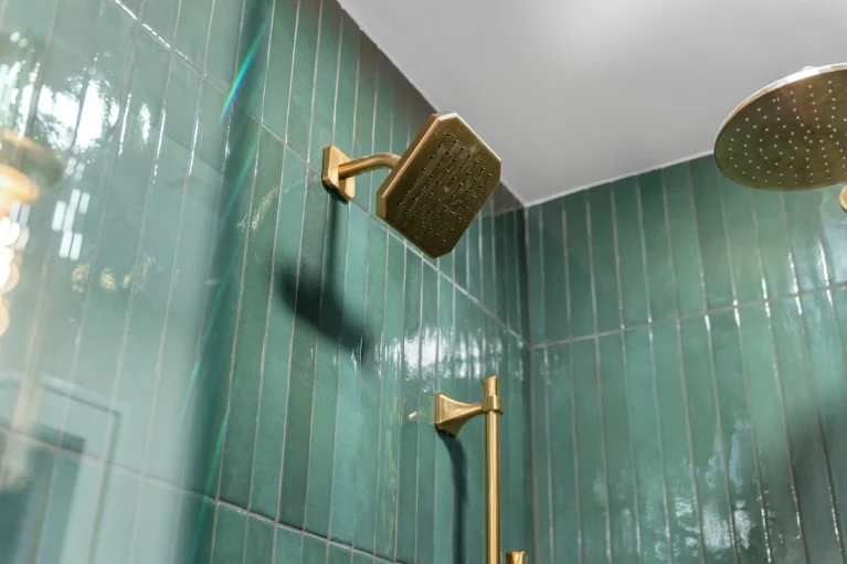 Close-up of the Kohler Purist widespread brass faucet and wood vanity in a Denver bathroom conversion.