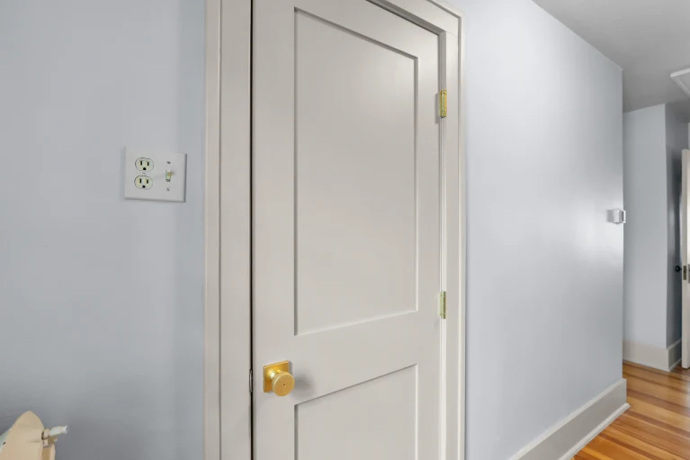 New full bath entry door with brass knob and hinges in the hallway of a West Highland Denver home.
