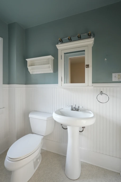 Original half bath with pedestal sink and toilet, before being converted into a full bathroom.