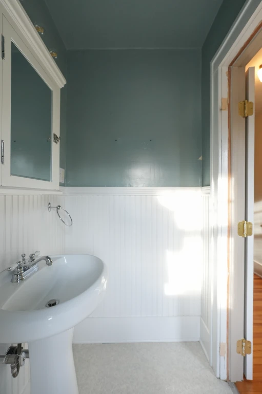 Original Denver powder room before conversion, with pedestal sink, white beadboard wainscoting, and teal upper walls.
