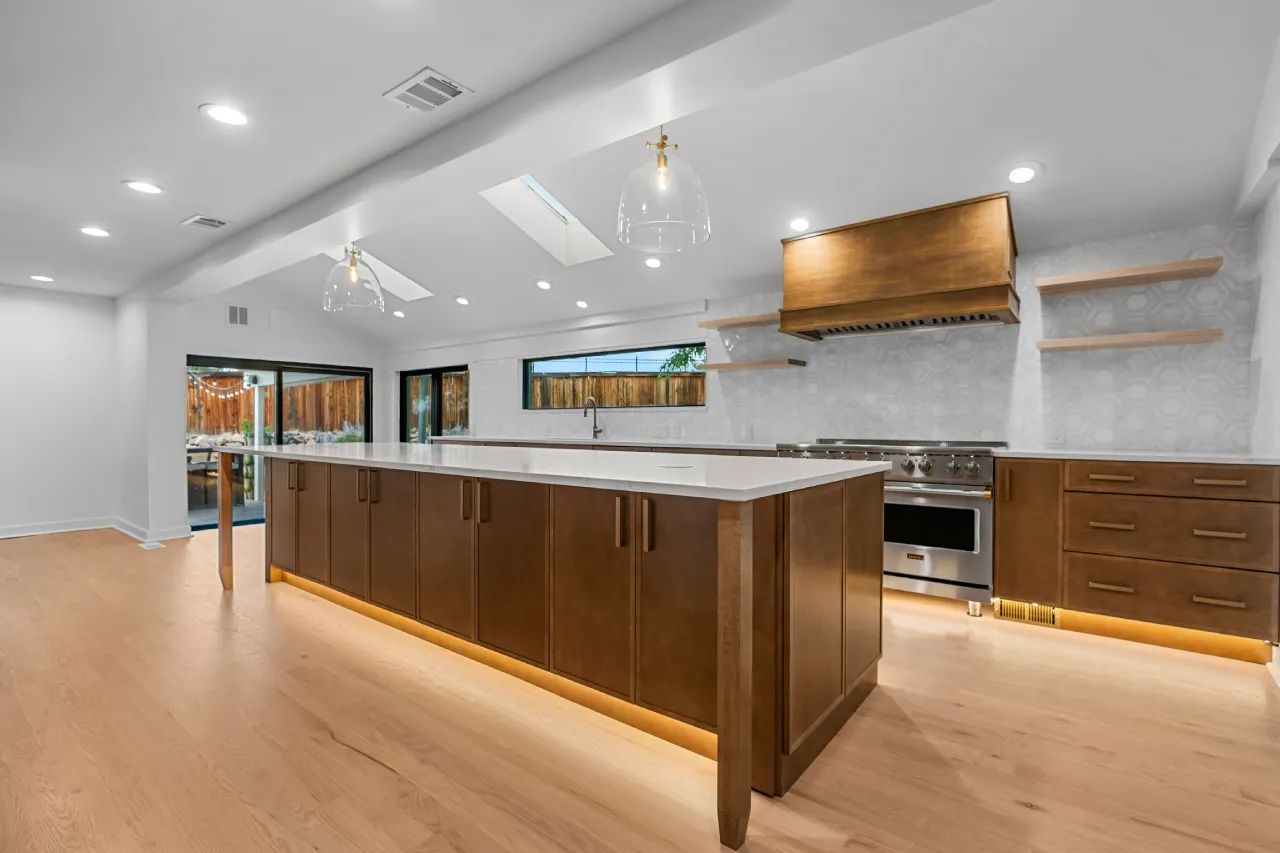 Kitchen remodel in Centennial, CO: the finished kitchen where the enclosed patio was, with island, Viking range, custom wood hood and doors to the covered patio